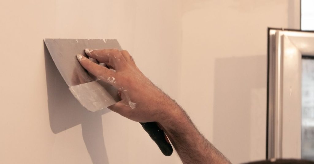 Hand applying plaster with trowel on wall