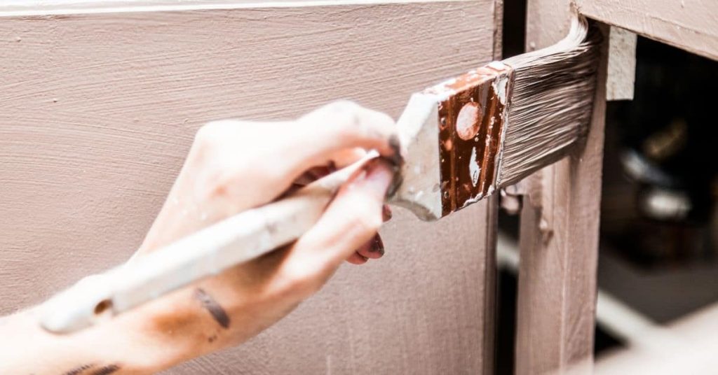 Hand painting wooden cabinet with paintbrush closeup