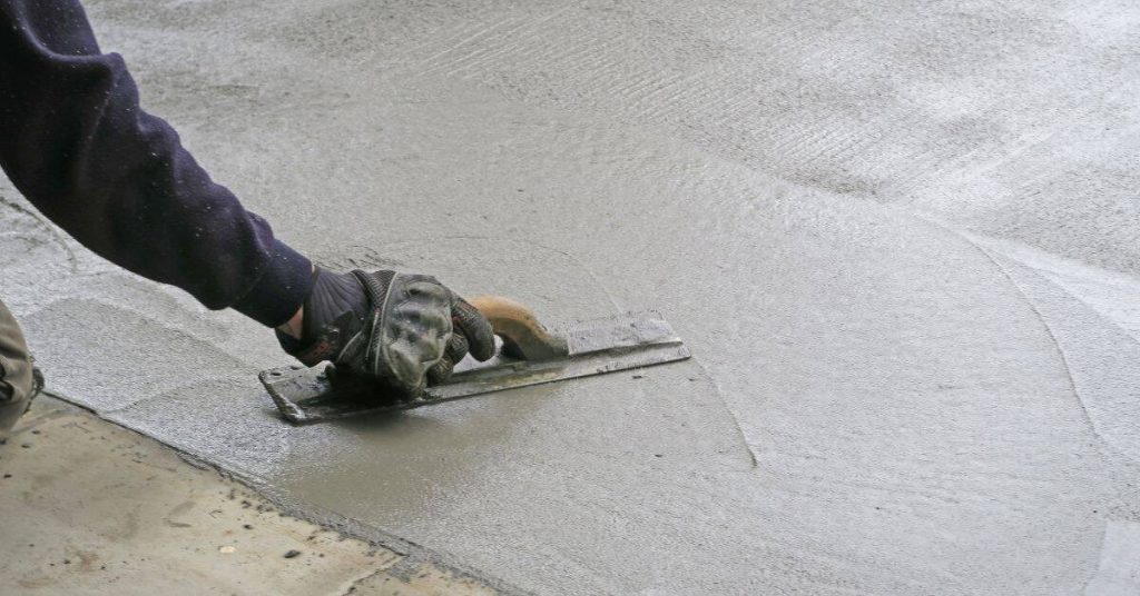 Hand smoothing freshly poured concrete slab with trowel