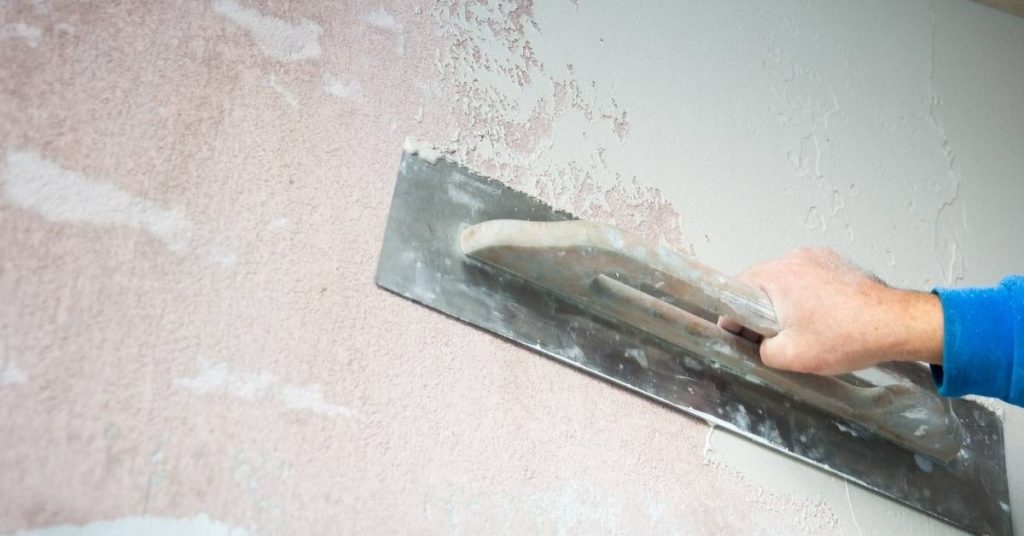 Hand smoothing lime plaster on wall with trowel