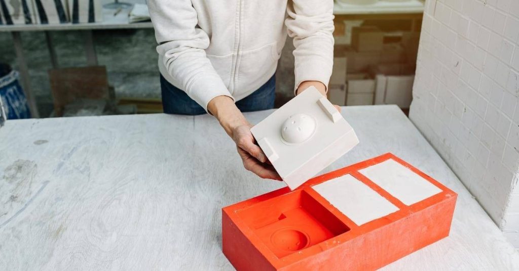 Hands holding plaster mold and casting on white table