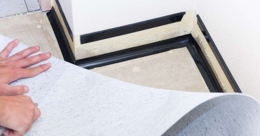 Hands installing flooring underlayment in a corner area