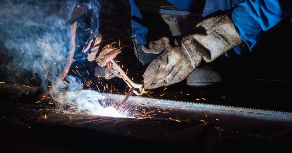 Hands welding metal with protective gloves and sparks