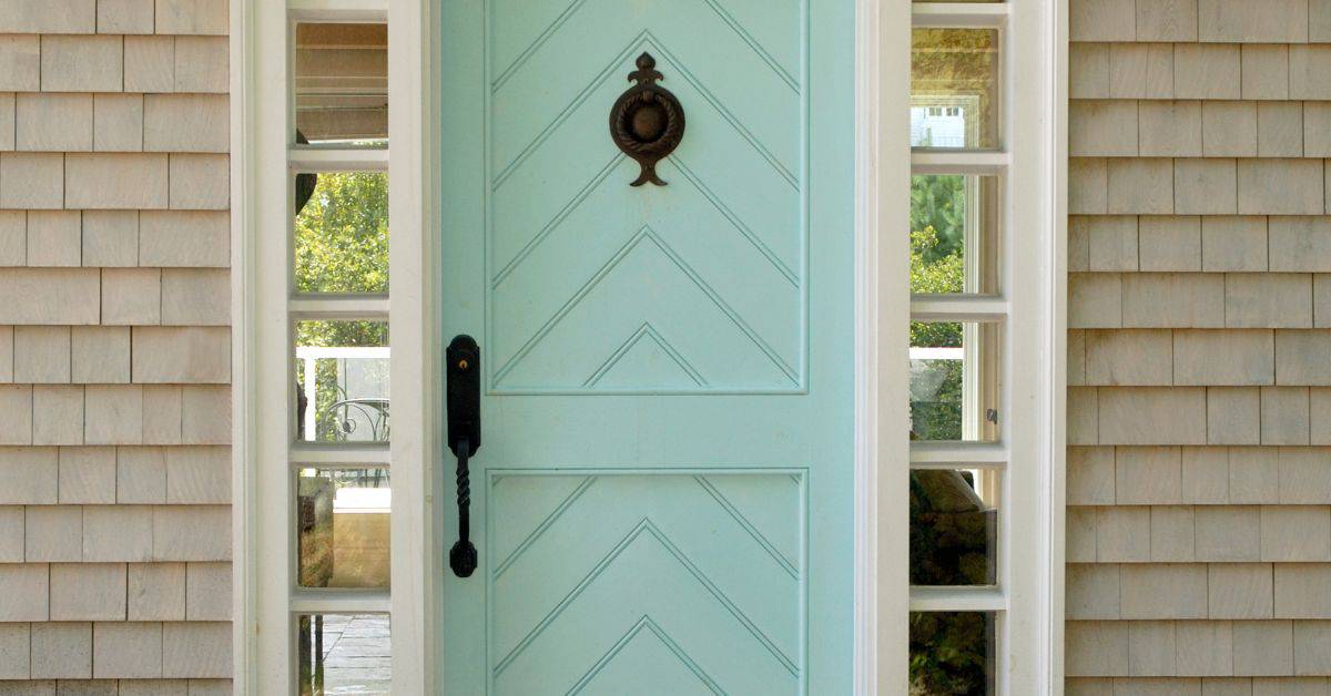 Light blue front door with sidelights and beige shingle siding