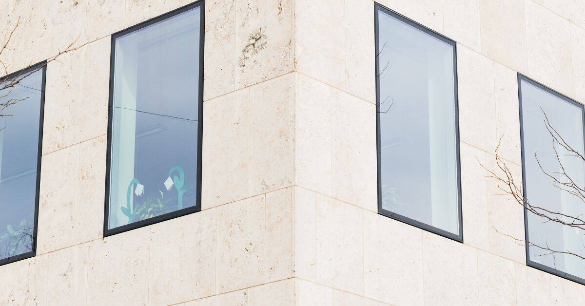 Corner of modern stone building with four large windows