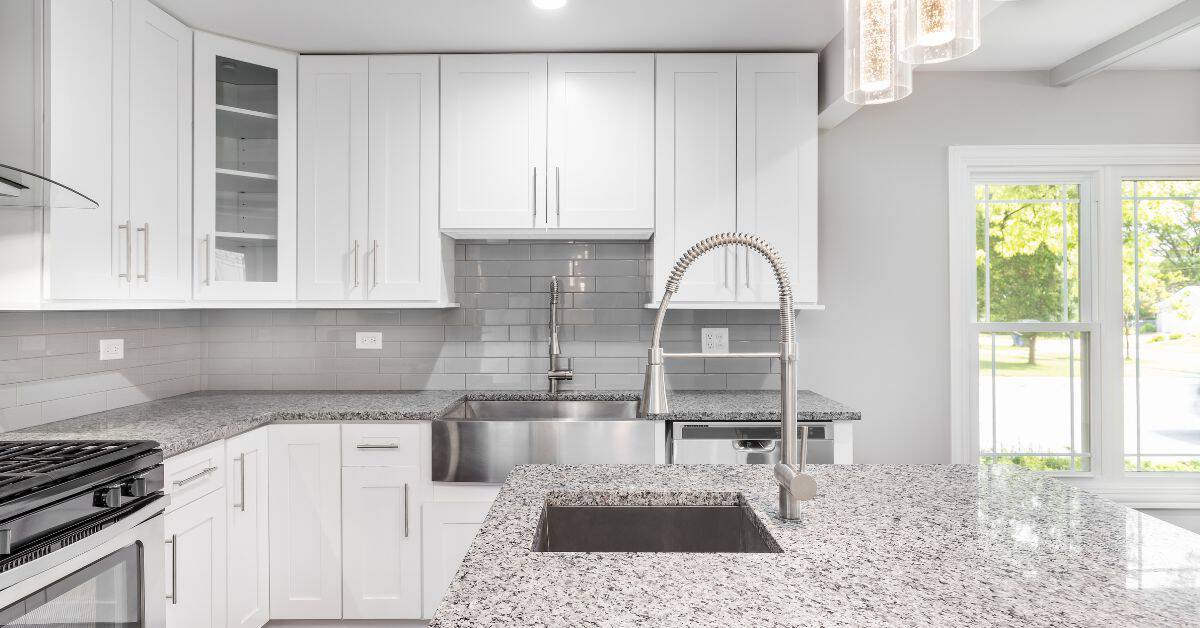 modern white kitchen with granite countertops and stainless steel sinks