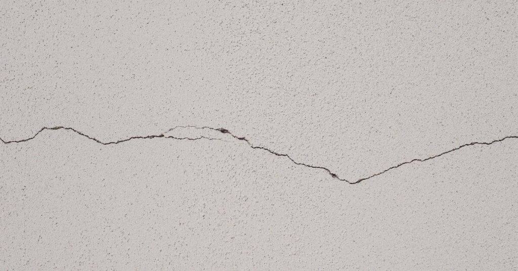 horizontal crack in white stucco wall surface