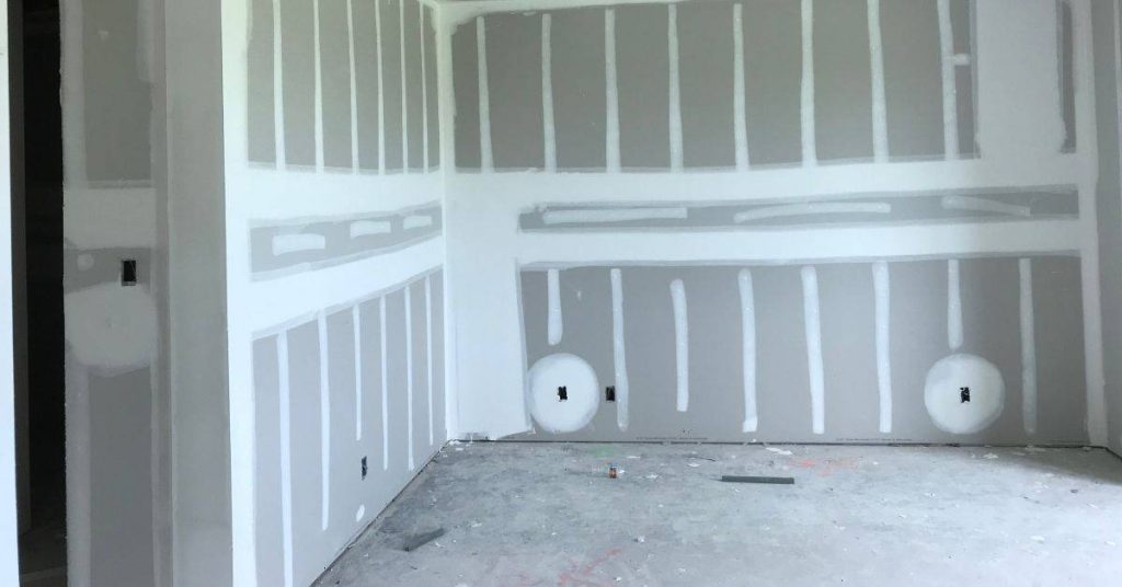 Interior room with drywall panels taped and mudded on walls