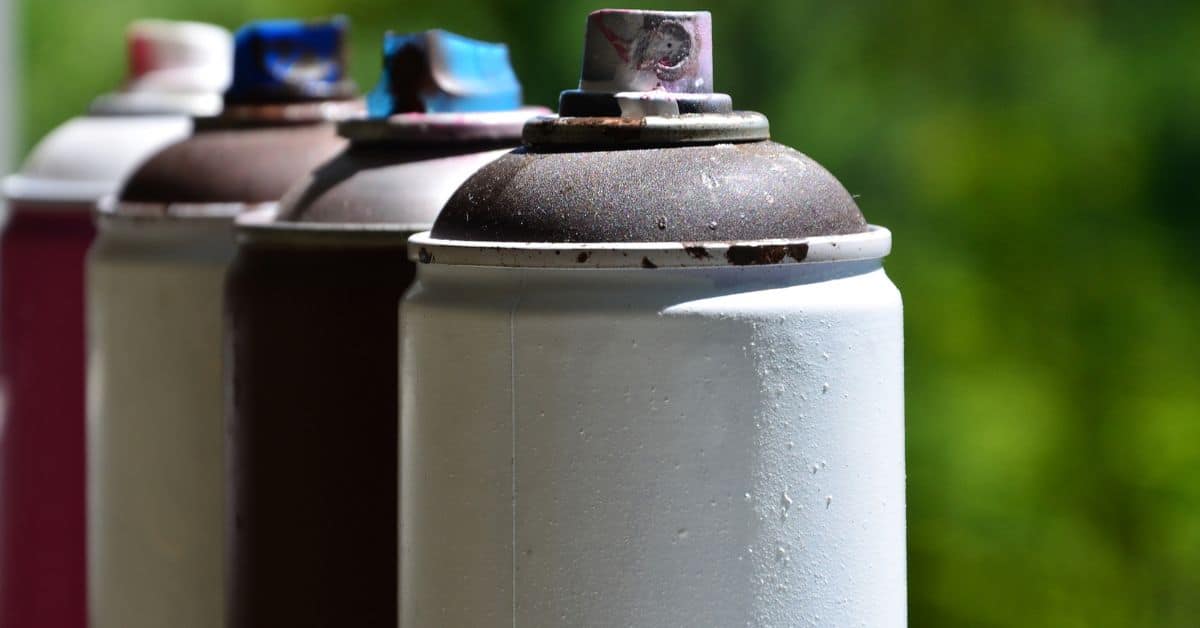 Close-up of used spray paint cans outdoors with blurred background