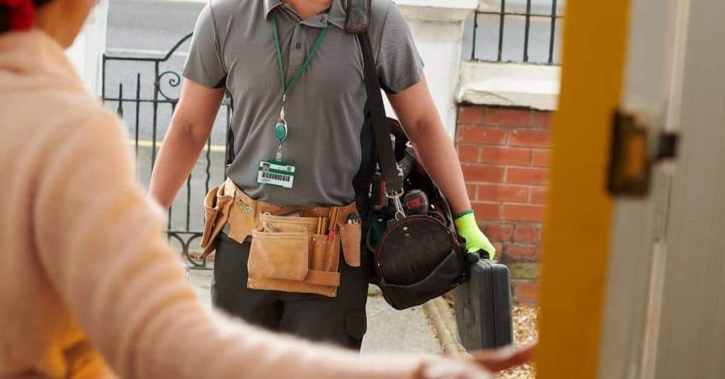 Man wearing tool belt and carrying tool bag and case