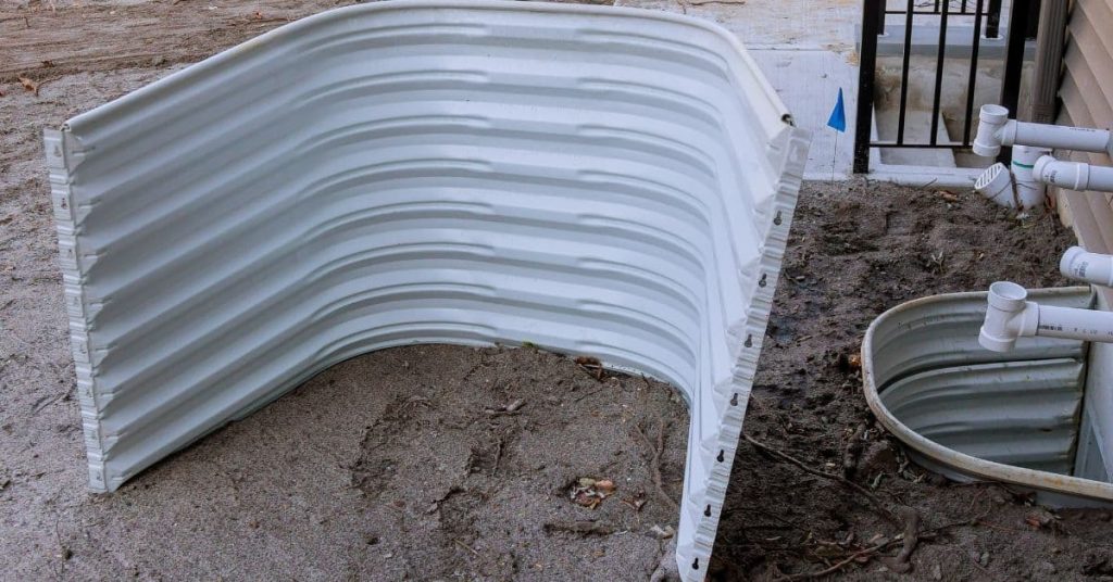 Metal window well next to house foundation