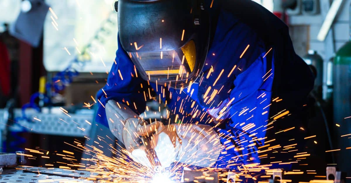 Person welding metal with sparks flying in workshop