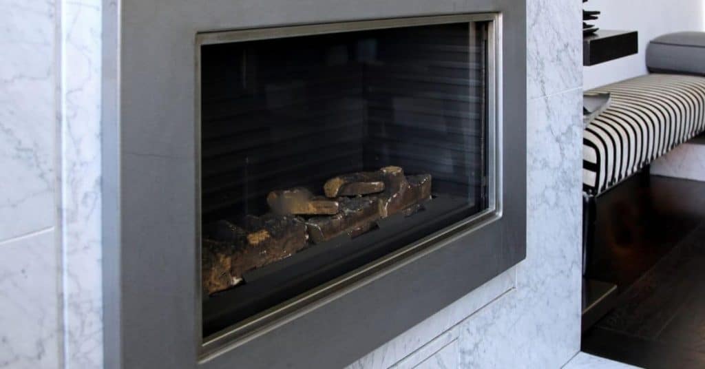 Modern gas fireplace with marble surround and striped bench nearby