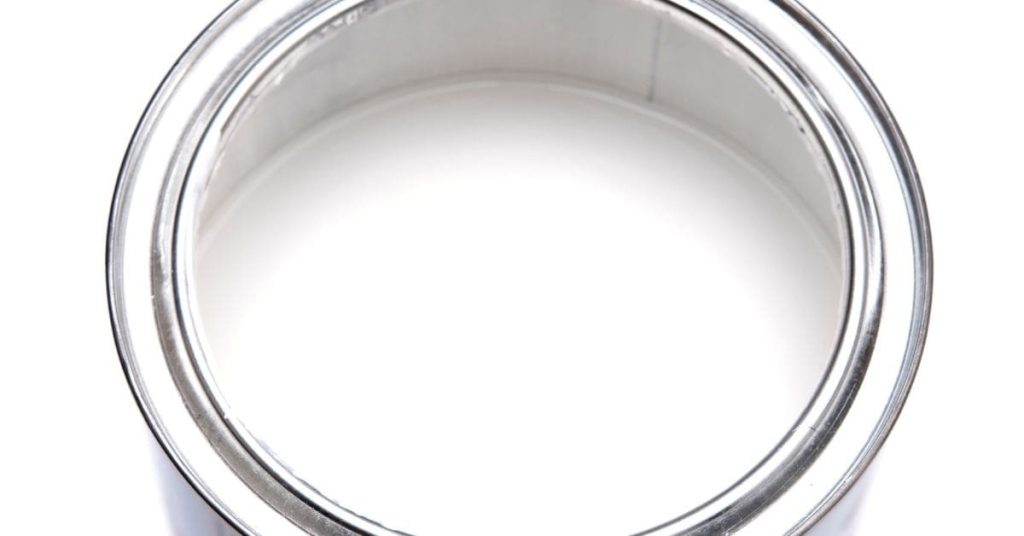 Open metal can filled with white paint
