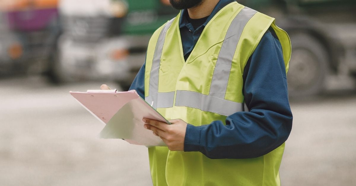 construction worker wearing reflective vest holding clipboard outdoors