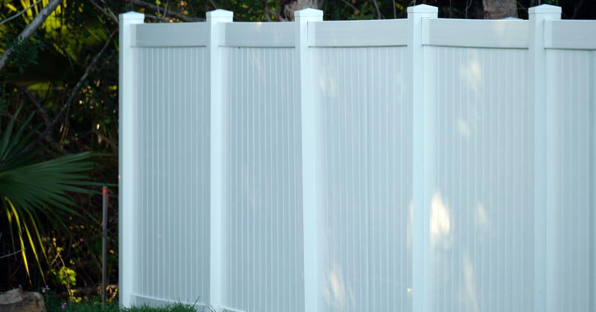white vinyl fence panels outdoors with trees in background