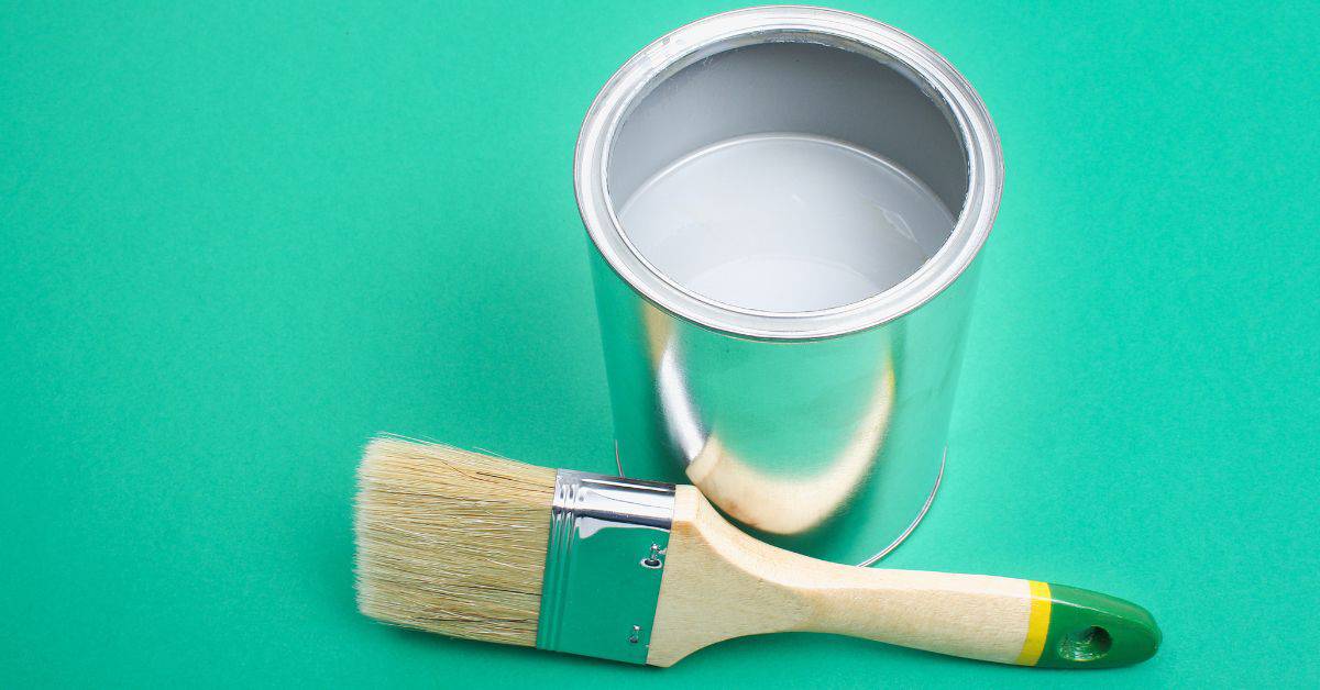 Open paint can next to paintbrush with green handle