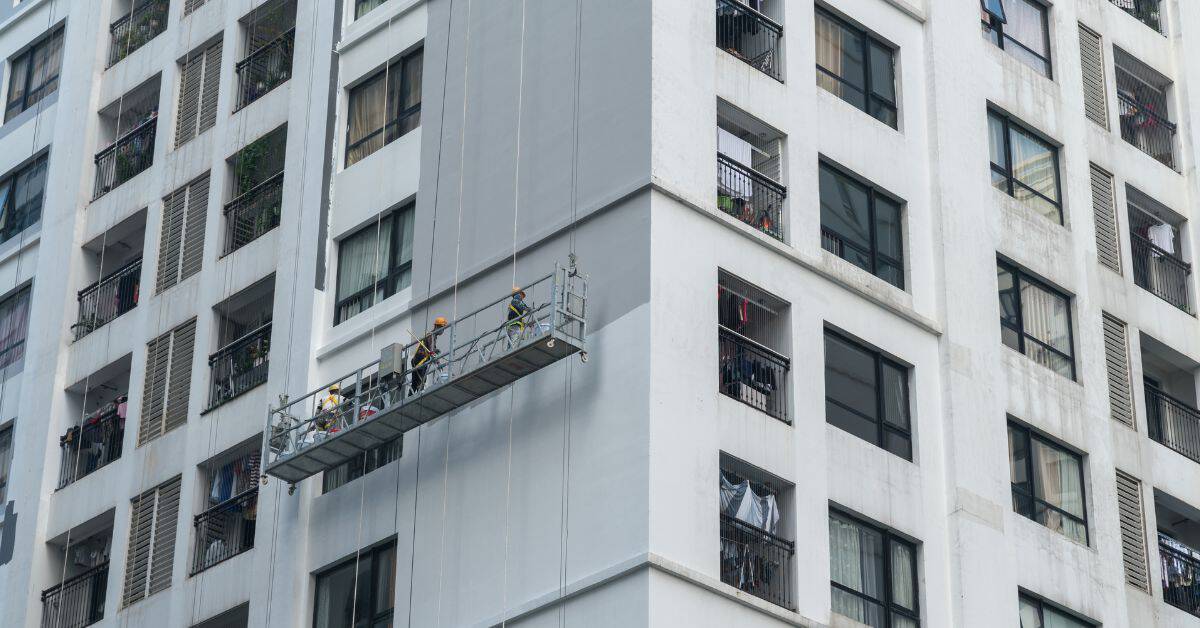 workers on suspended platform painting high rise building exterior