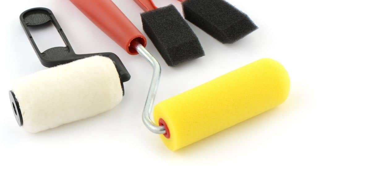 Two paint rollers and two foam paint brushes on white background