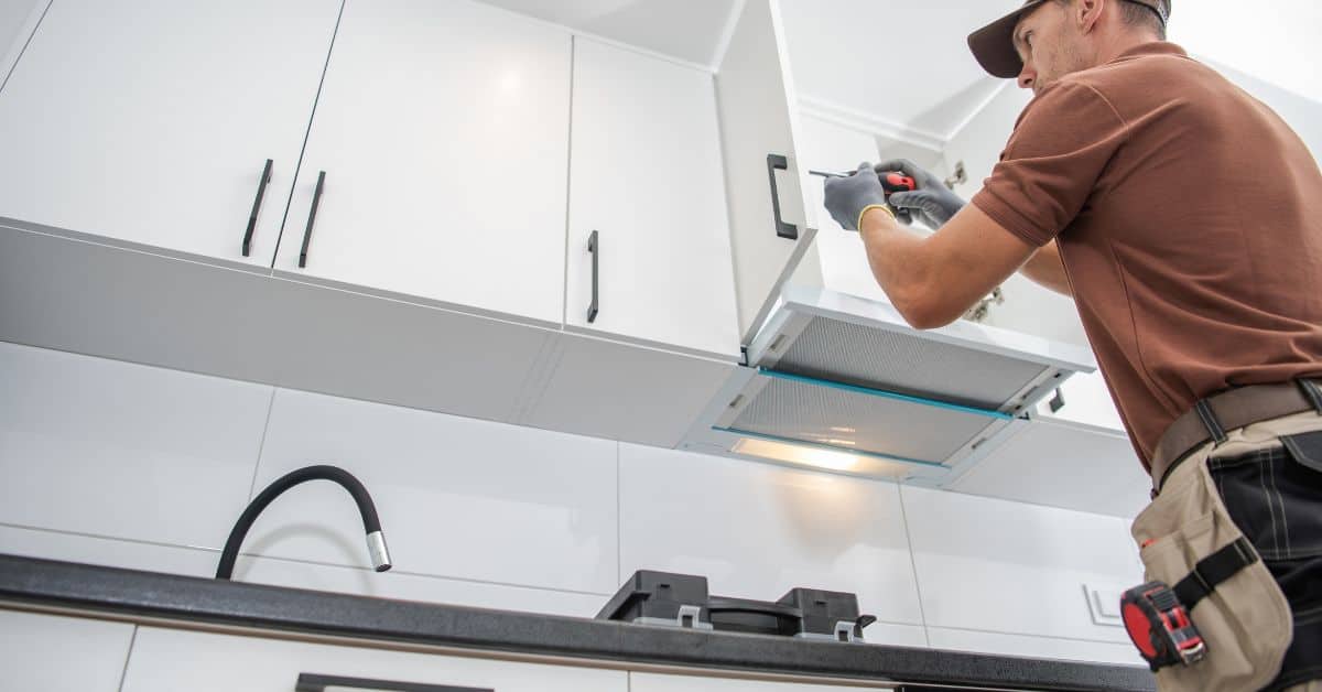 person installing hardware on white kitchen cabinet door