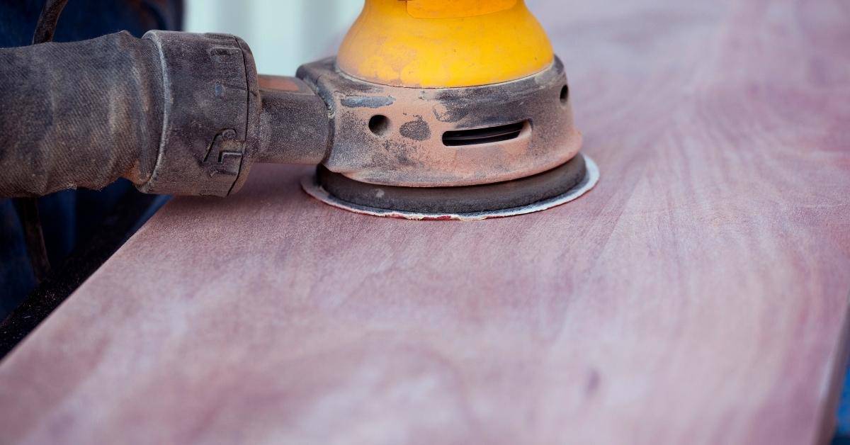 Orbital sander smoothing wooden surface close up