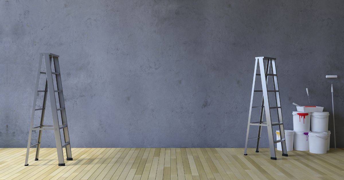 Two ladders and several paint buckets with rollers on wooden floor