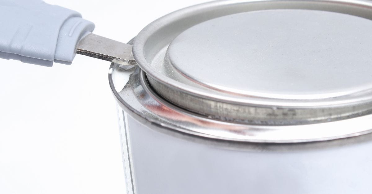 Close-up of paint can lid being opened with a paint can opener