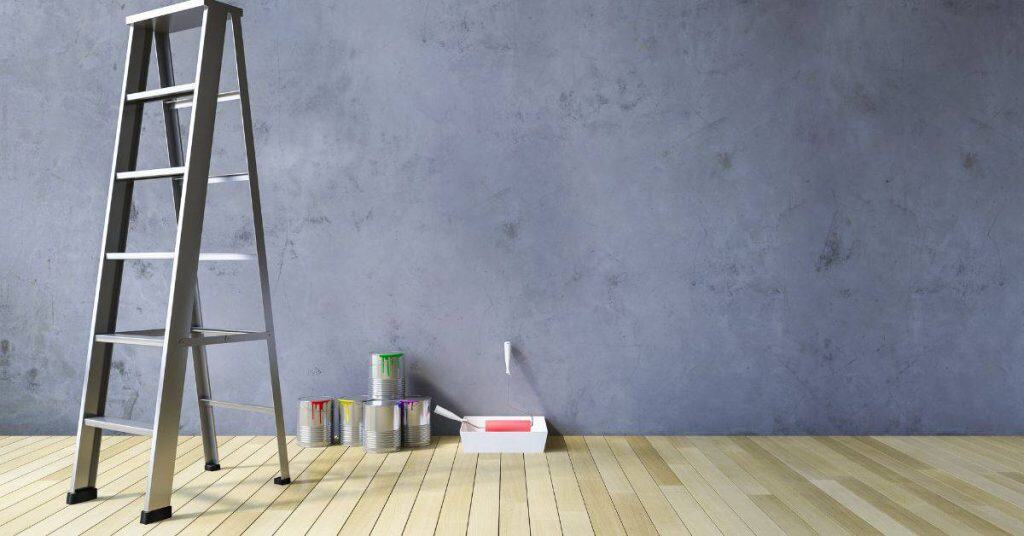 Aluminum ladder next to paint cans and roller on wooden floor