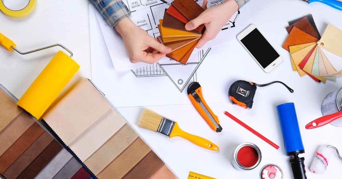 Person holding brown paint color swatches over house plans