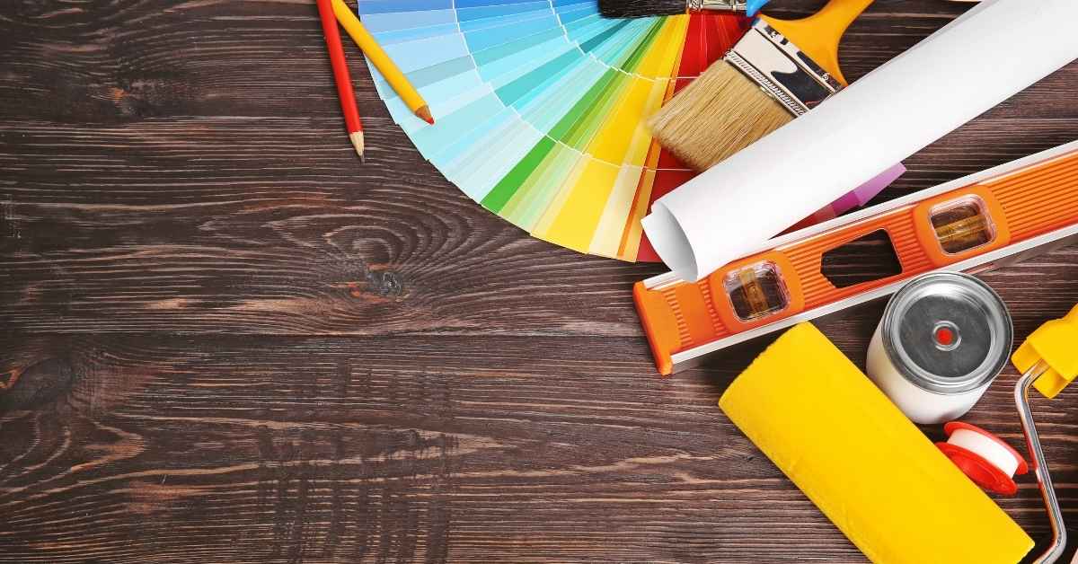 Color swatches brush roller level pencils on wooden surface