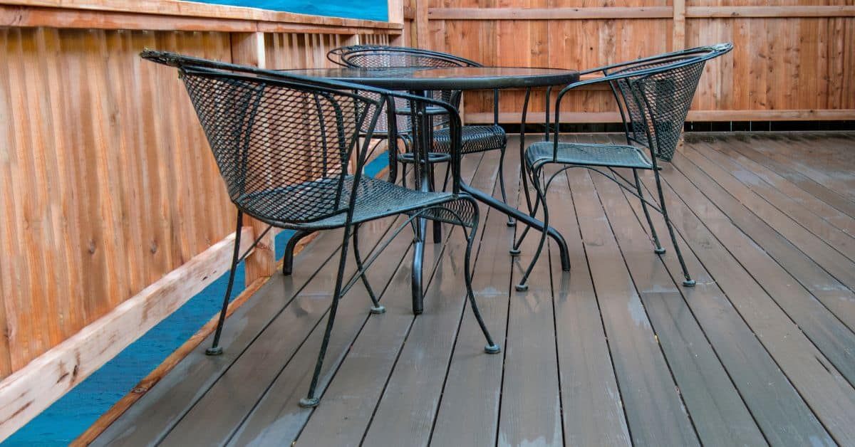 Metal patio table and chairs on freshly coated wooden deck floor