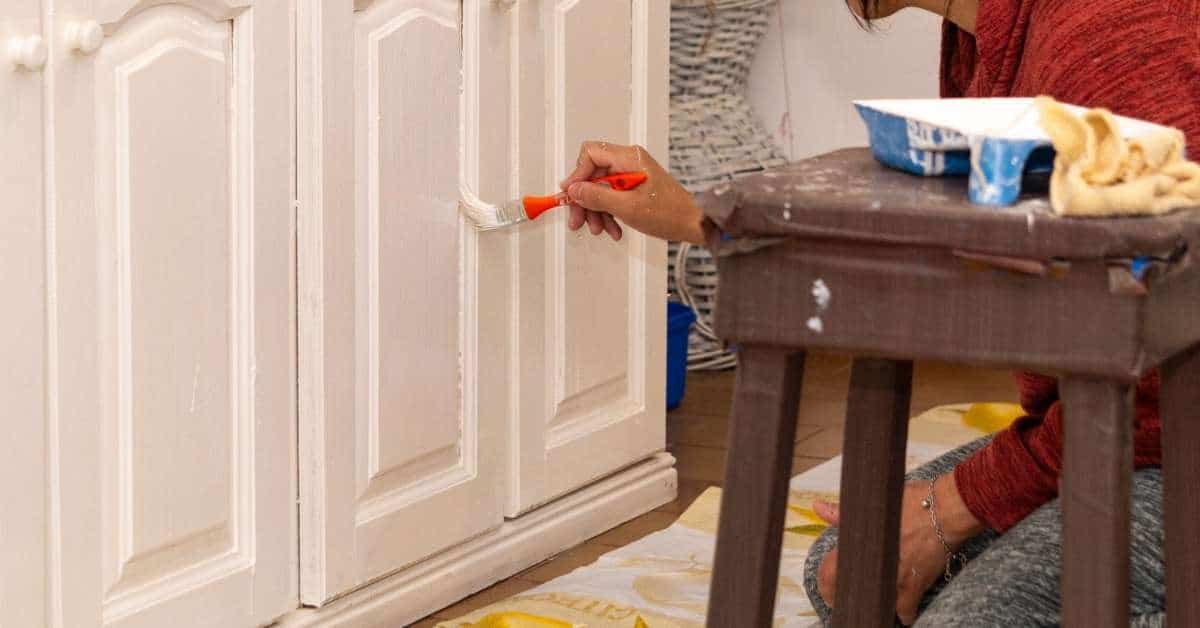 Person painting white cabinet doors with small brush