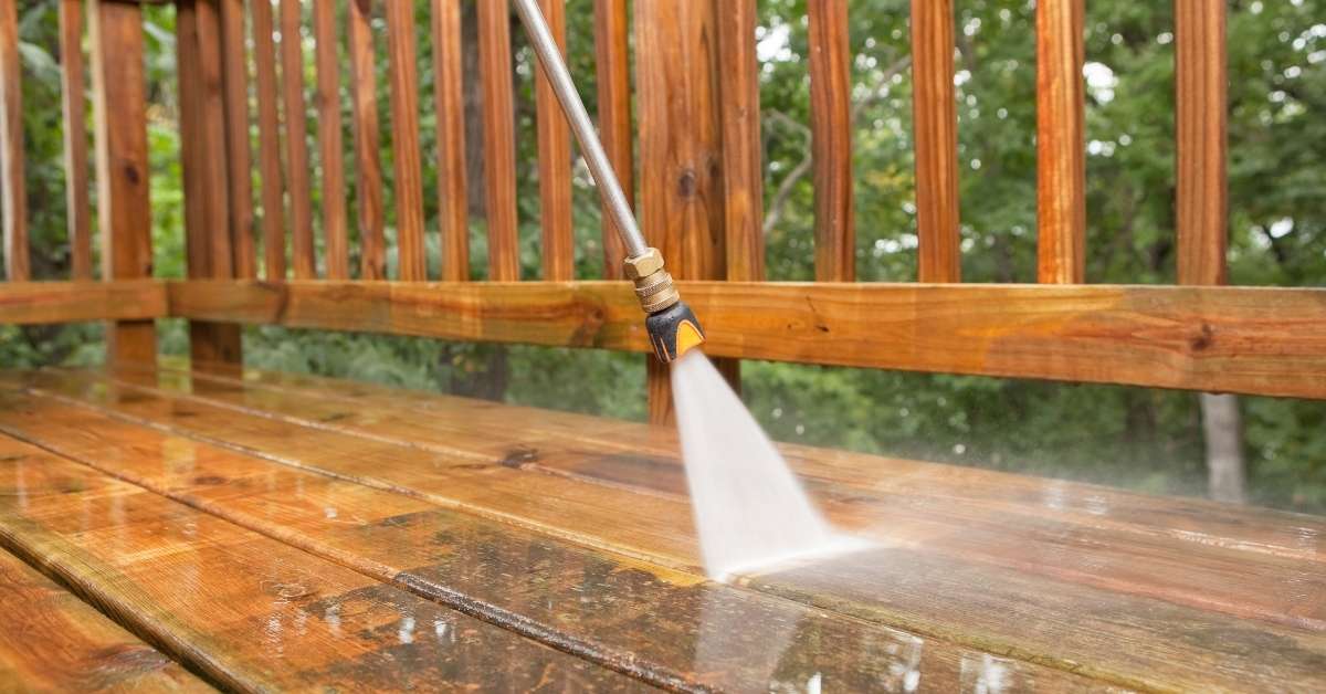 Pressure washing wooden deck with water spray nozzle