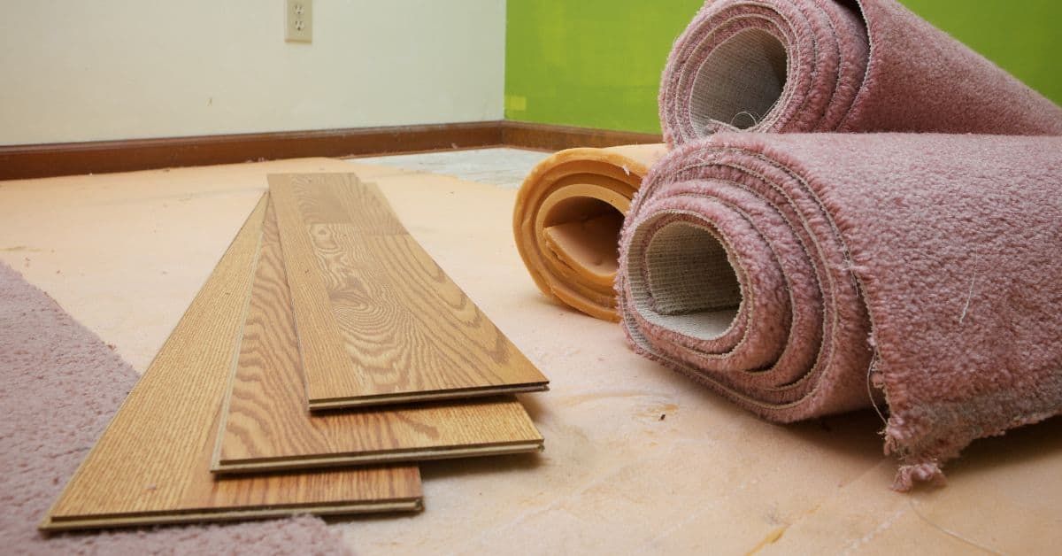 Rolled pink carpet and wooden flooring planks on floor