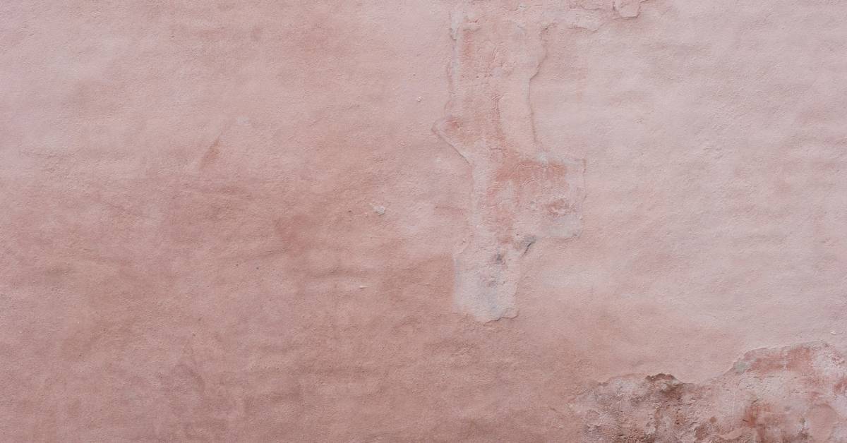 close-up of weathered pink stucco wall with uneven texture