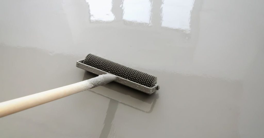 Paint roller with textured surface applying coating on floor