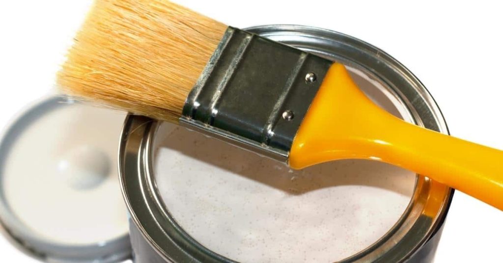 Paintbrush resting on an open can of white paint