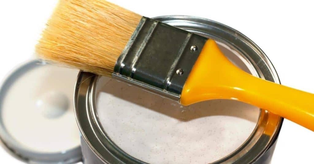 Paintbrush resting on open can of white paint