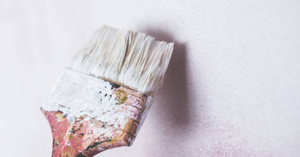 Paintbrush with white paint against white background