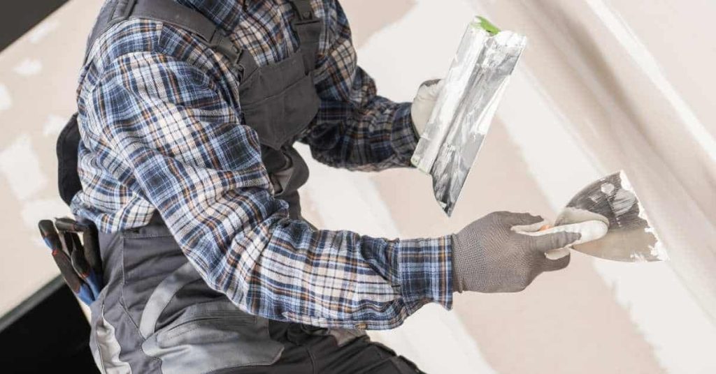 Person applying plaster to plaster cornice with trowel and spatula