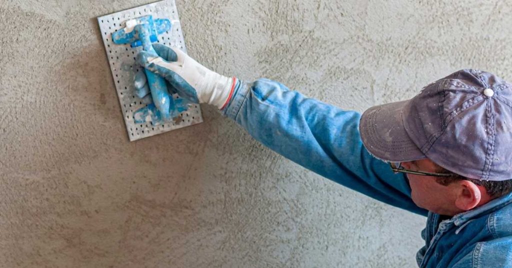 Person applying skip-trowel stucco texture with trowel