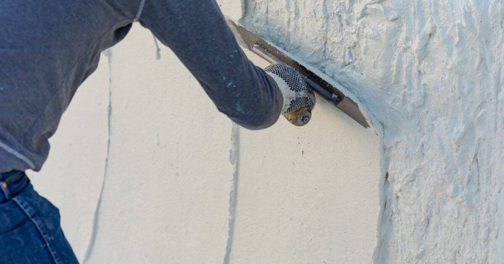 Person applying stucco texture on exterior wall