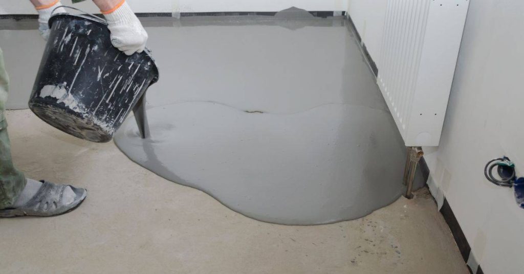 Person pouring gray self-leveling compound on concrete floor