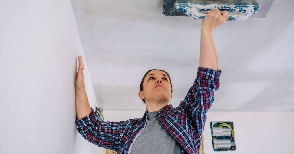 Person smoothing plaster on ceiling with trowel