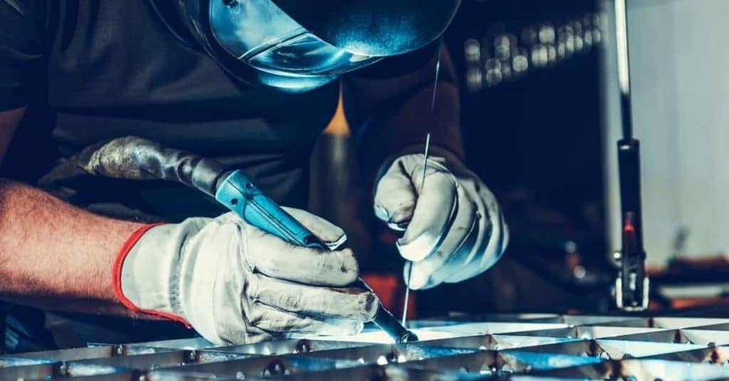 Person welding metal grid wearing gloves and helmet