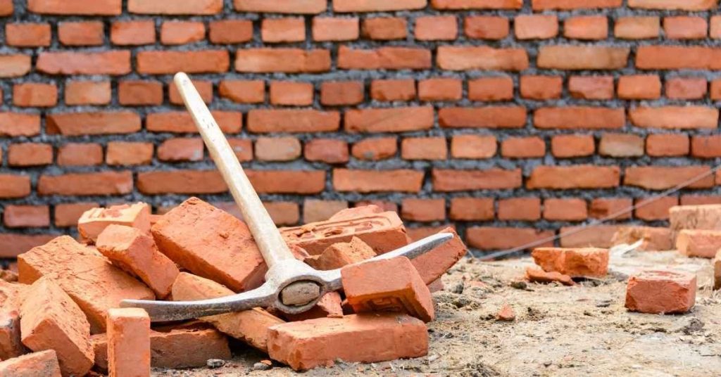 Pile of red bricks with a pickaxe resting on top