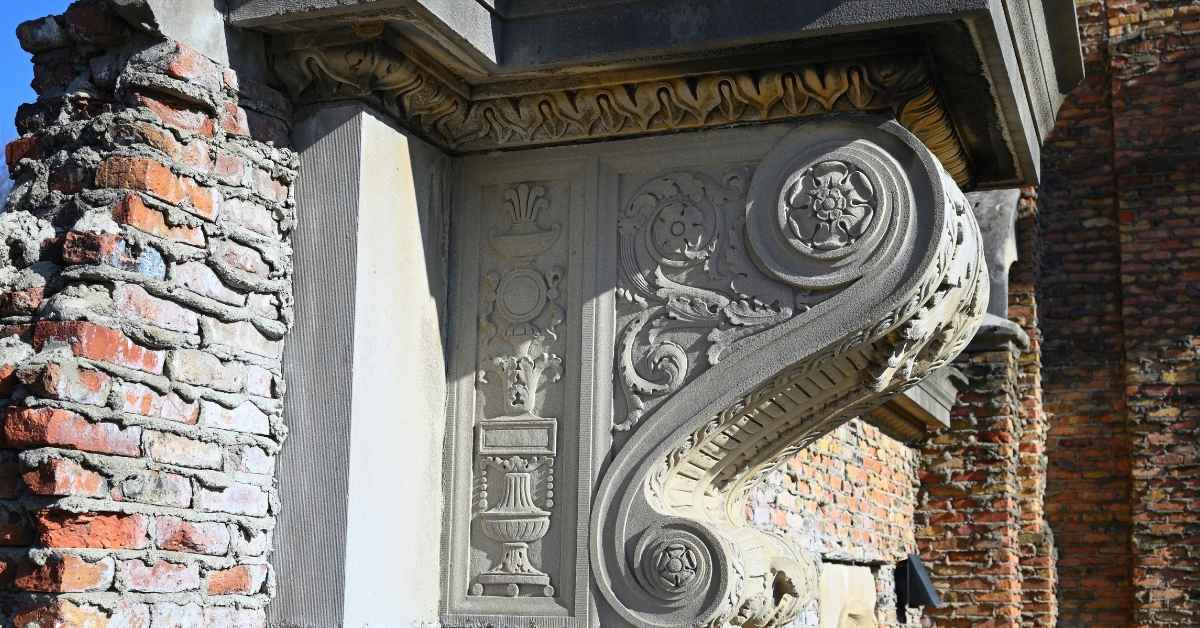 decorative plaster corbel detail on brick wall under sunlight
