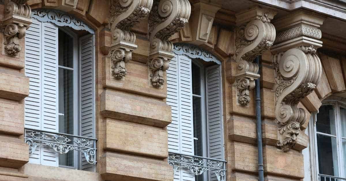 Building facade with decorative plaster corbels and shuttered windows