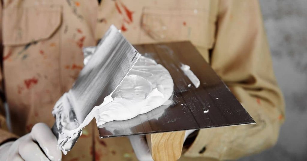 Plaster on trowel and hawk held by person in work clothes