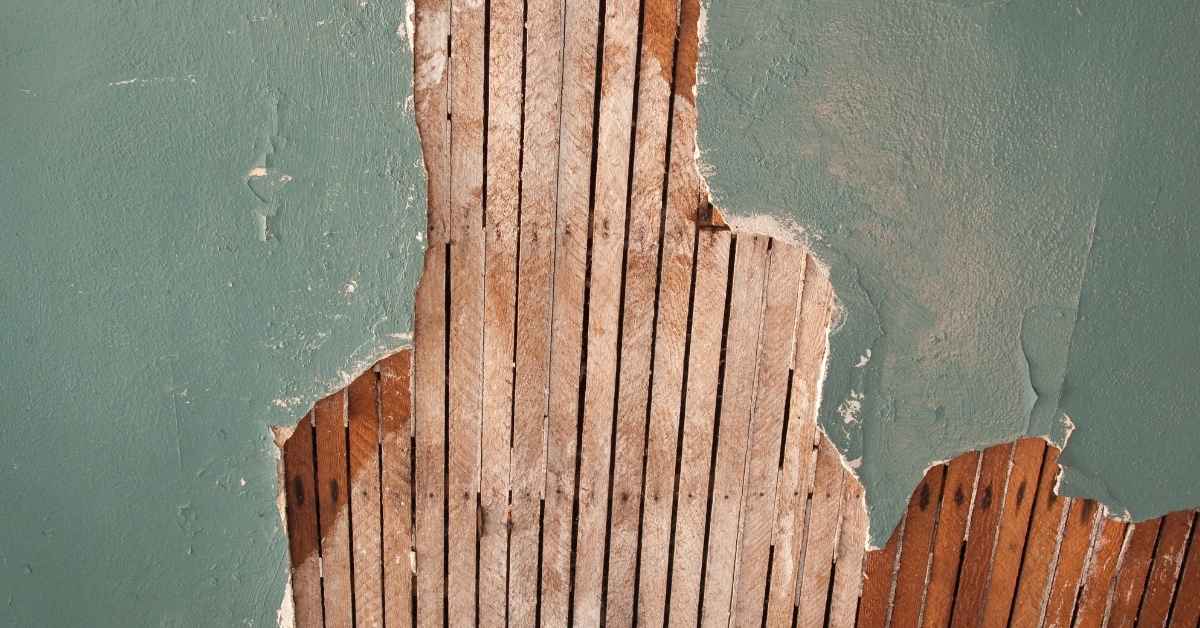 Exposed wooden lath under damaged plaster on wall